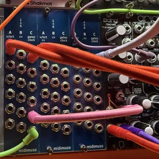 Photograph of three of the frontpanels from this project in among other eurorack modules, with wires connecting them