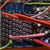 Photograph of three of the frontpanels from this project in among other eurorack modules, with wires connecting them